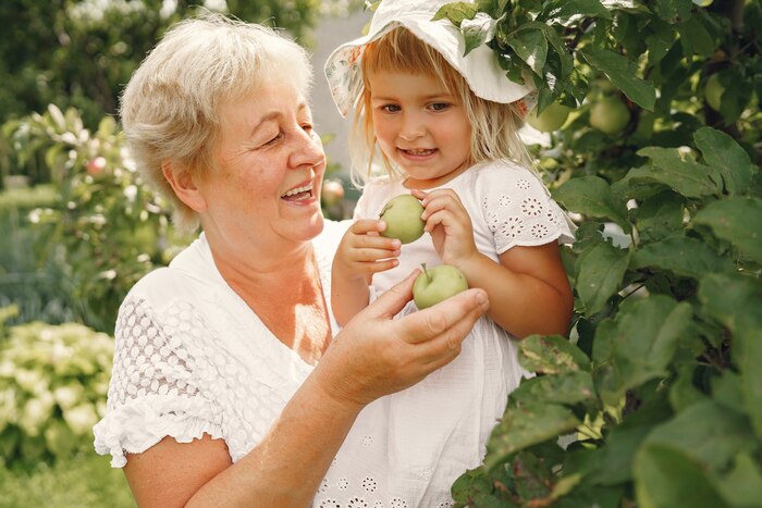 Grandmother and granddaughter together, hugging and joyfully laughing in a flowering apricot garden in april. family outdoors lifestyle.